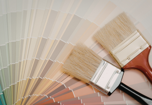 Two paintbrushes laid over a color wheel.